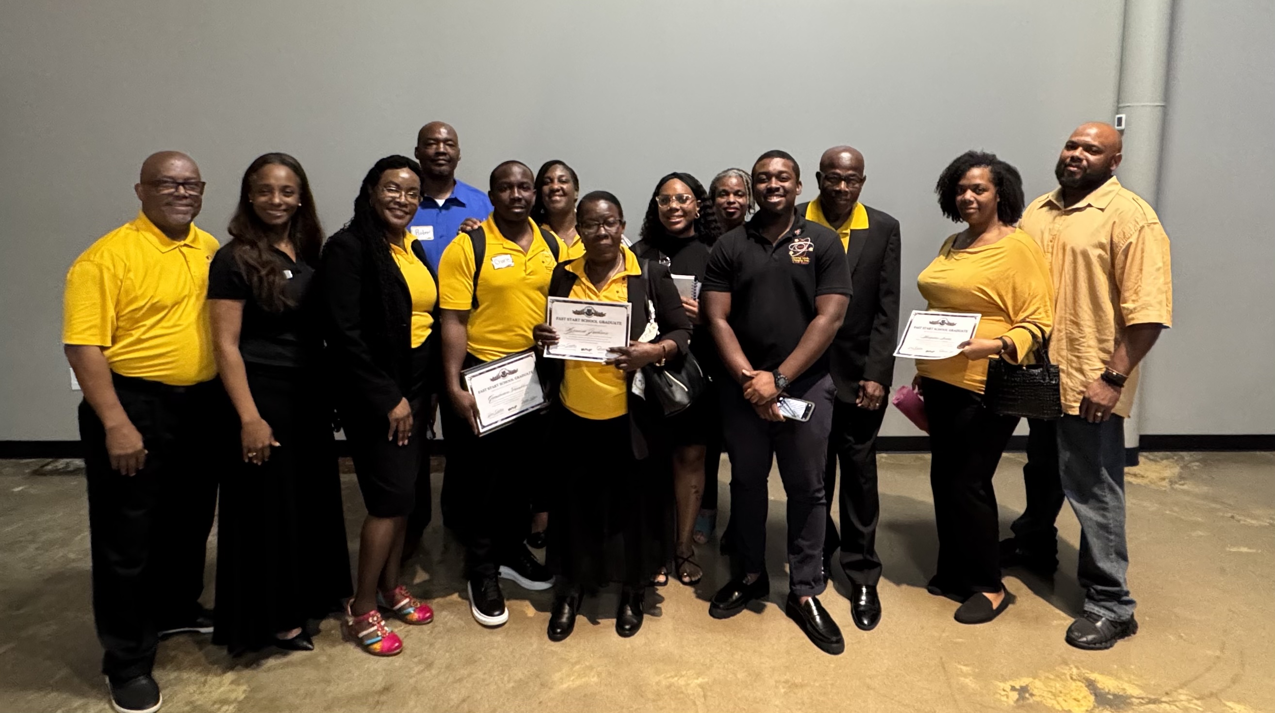 A large group of Catalysts team members, many dressed in gold and black, posing together indoors