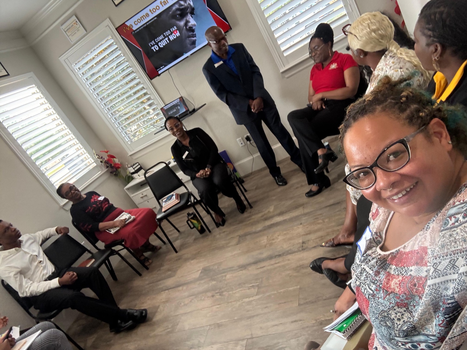 A smiling attendee takes a selfie with a seated training group behind her