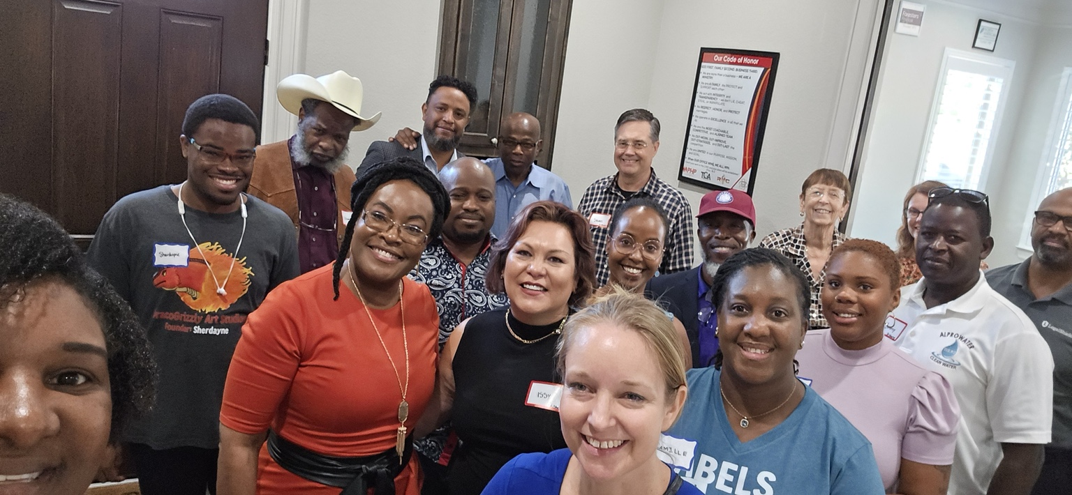 A large group selfie of smiling attendees indoors
