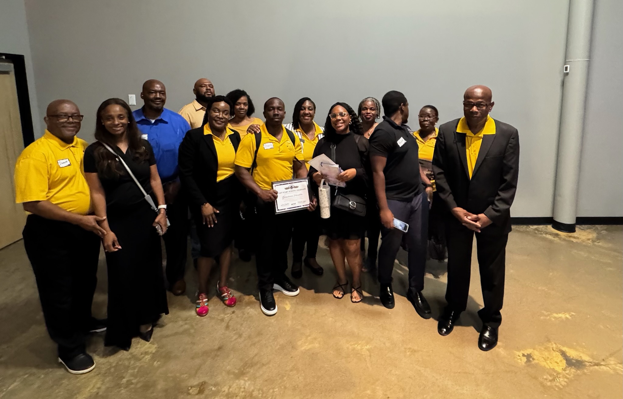 A large group of Catalysts team members, many dressed in gold and black, standing together indoors